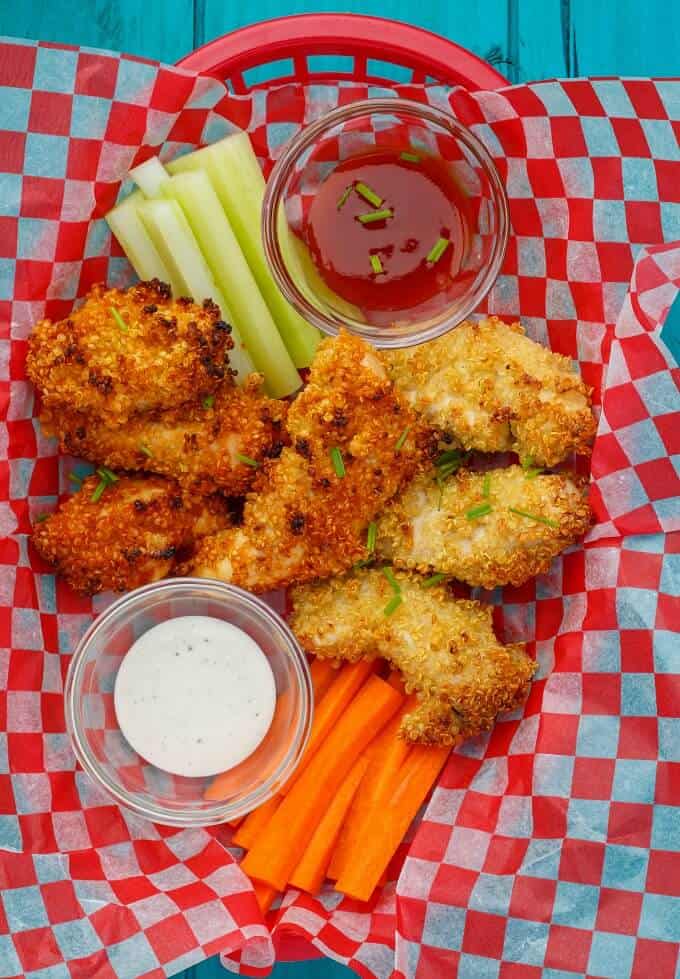Quinoa-Crusted Chicken Nuggets with vegetables and dips on paper sheet