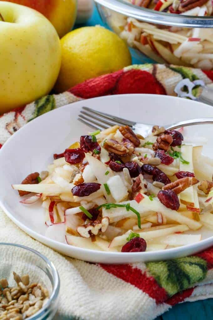 Raw Apple Salad (Vegan & GF) on white plate with fork on piece of cloth with apples