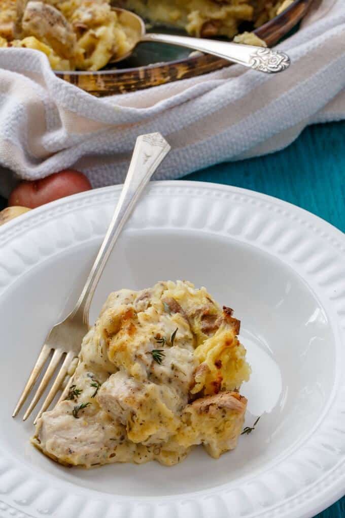 Mashed Potato Chicken Pie on white plate with fork, rest of dish in casserole in the background