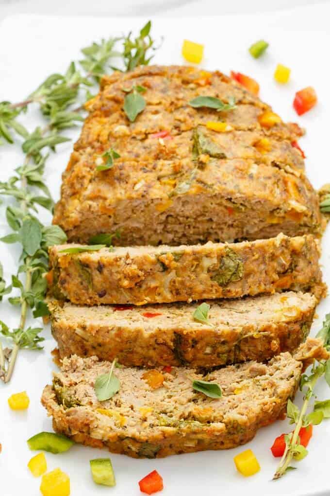 Slow Cooker Turkey Meatloaf sliced on white tray with herbs and vegetables