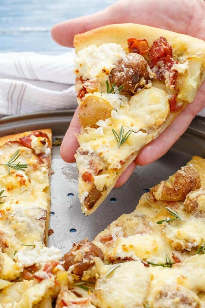 Thin Crust Bacon Potato Pizza slice held by hand on big plate
