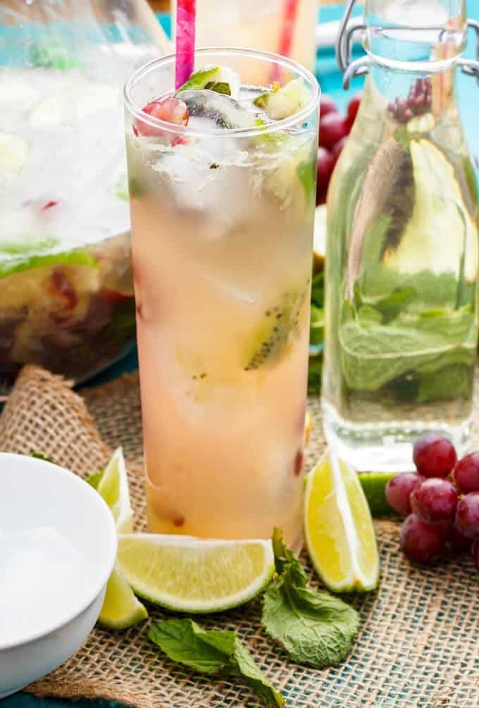 Fresh Kiwi-Grape Mojitos in glass cup with straw and in glass pitcher, fresh limes, grapes on the table