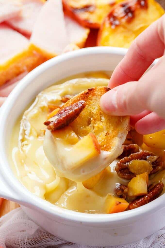 Grilled Maple-Butter Peach Camembert with Maple Pecans & Peameal Bacon in white bowl, dish held by hand