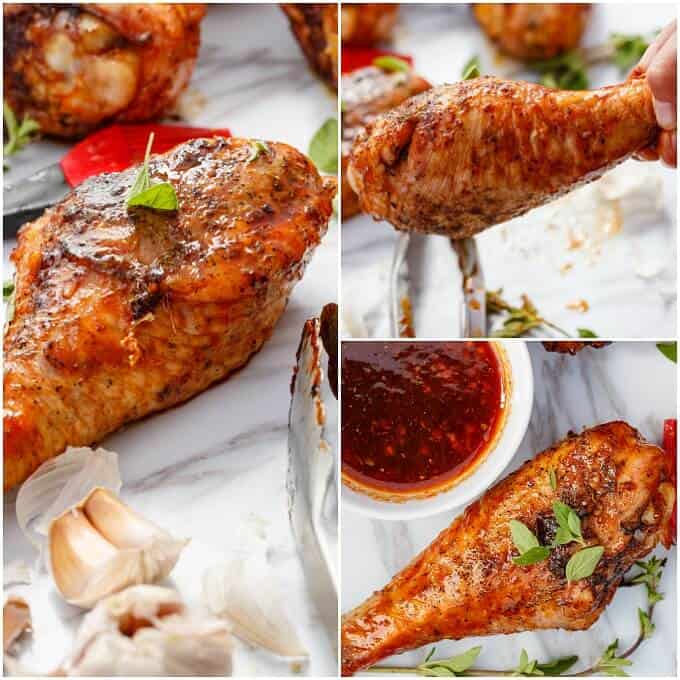 Grilled Sriracha Turkey Drumsticks on white table, held by hand, garlic, herbs bowl with sauce and red brush on white table
