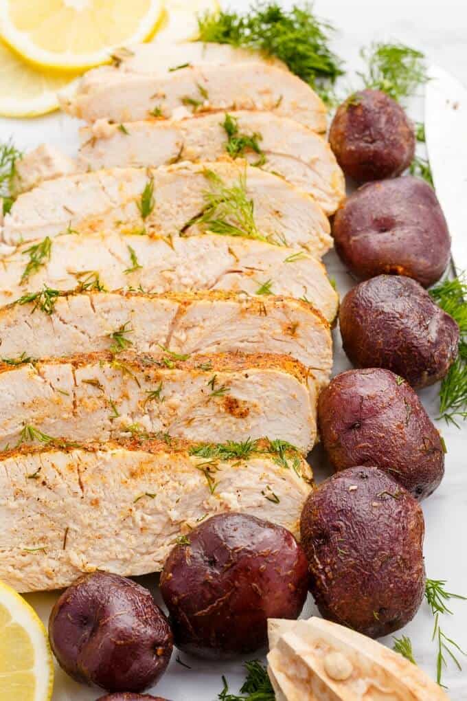Slow Cooker Lemon-Dill Turkey Breast  on white tray with potatoes and herbs