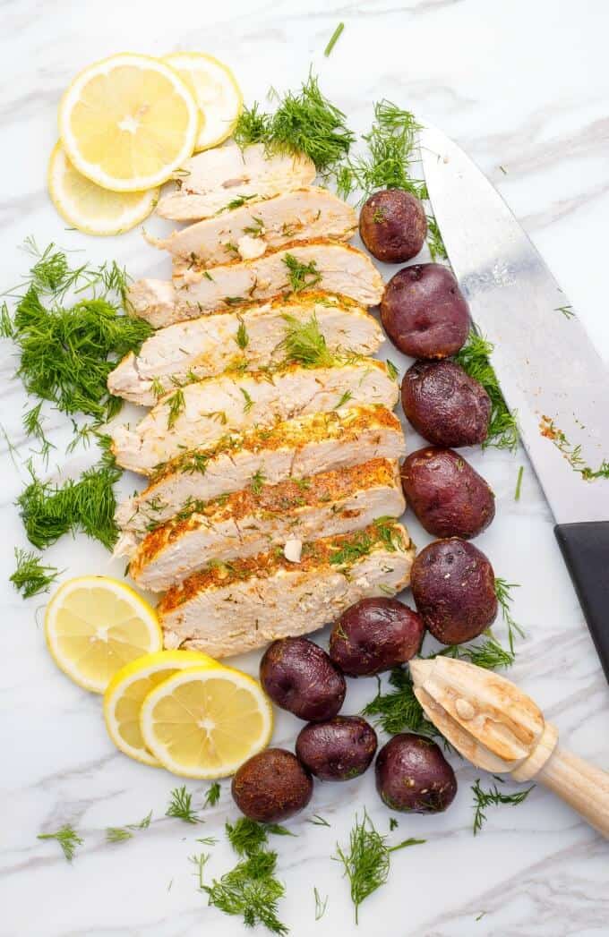 Slow Cooker Lemon-Dill Turkey Breast  on white table with lemons slices, potatoes, herbs, knife and kitchen wooden tool