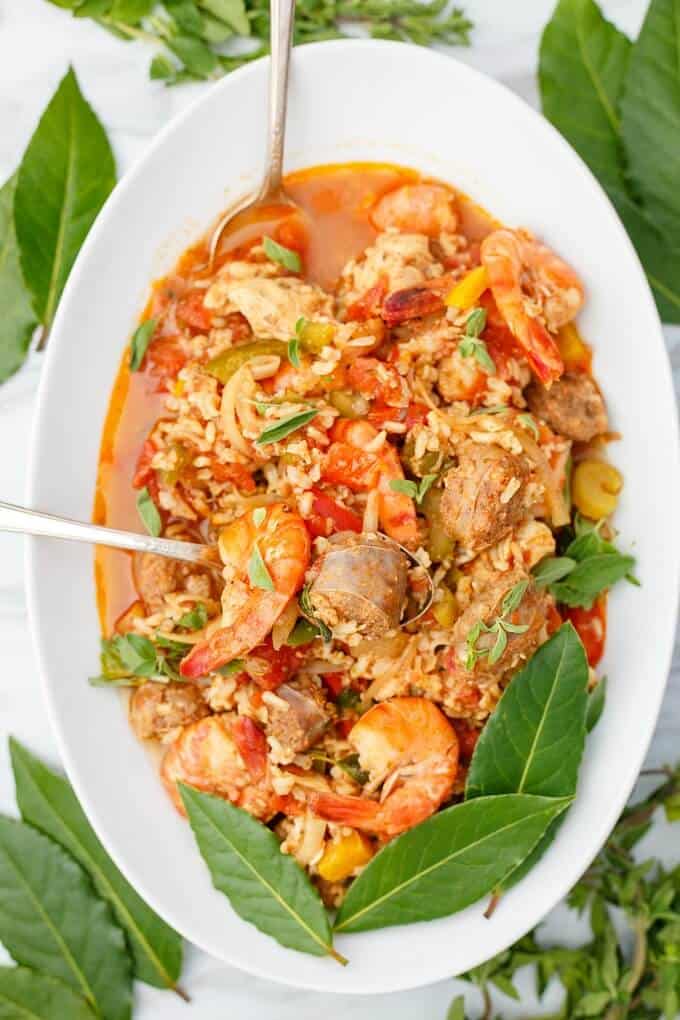 Easy Slow Cooker Jambalaya on white tray with spoons and herbs (Grocery Gateway)