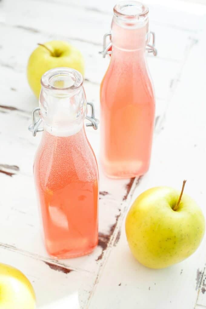 Homemade Apple-Infused Simple Syrup in glass bottles with apples around