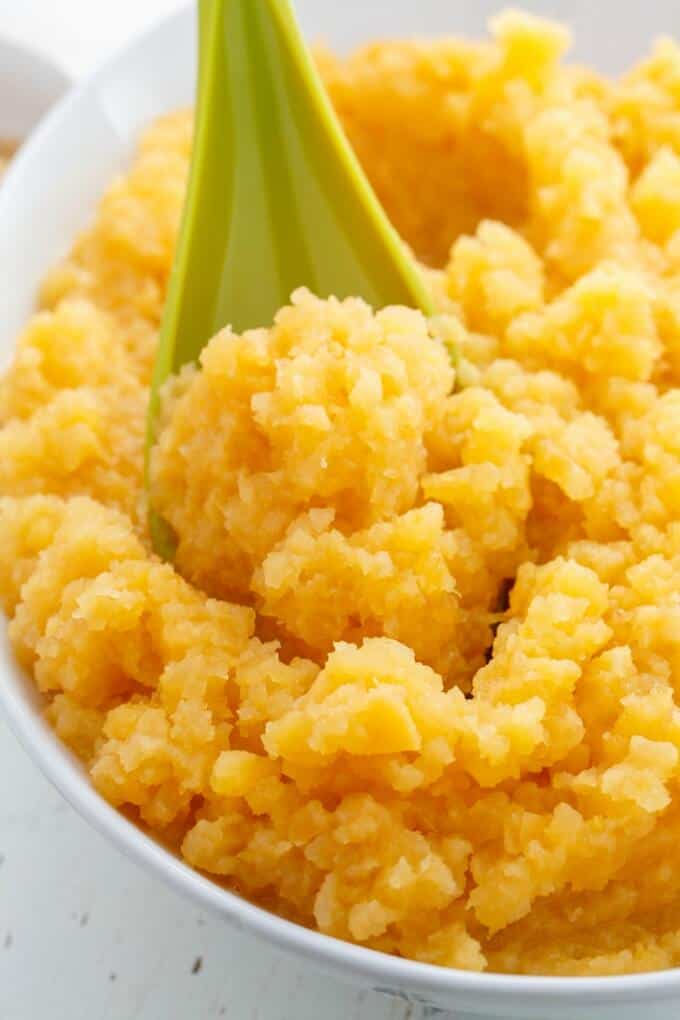 Mashed Rutabaga in white bowl with green spatula