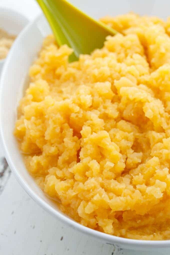 Mashed Rutabaga in white bowl with green spatula