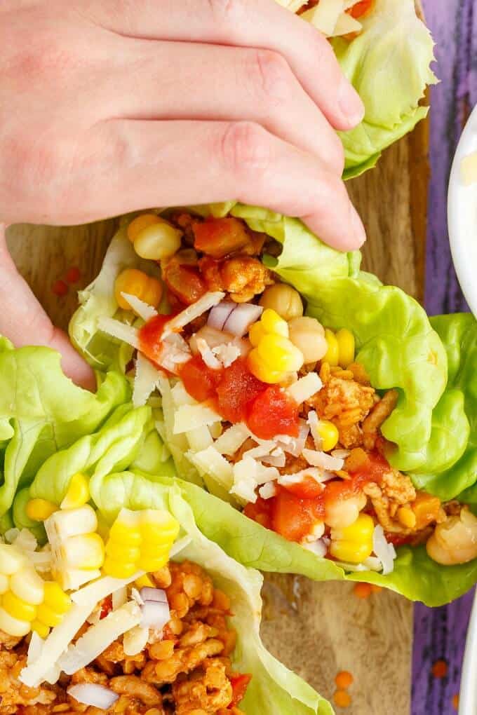 Taco Turkey-Lentil Lettuce Wraps held by hand on wooden pad