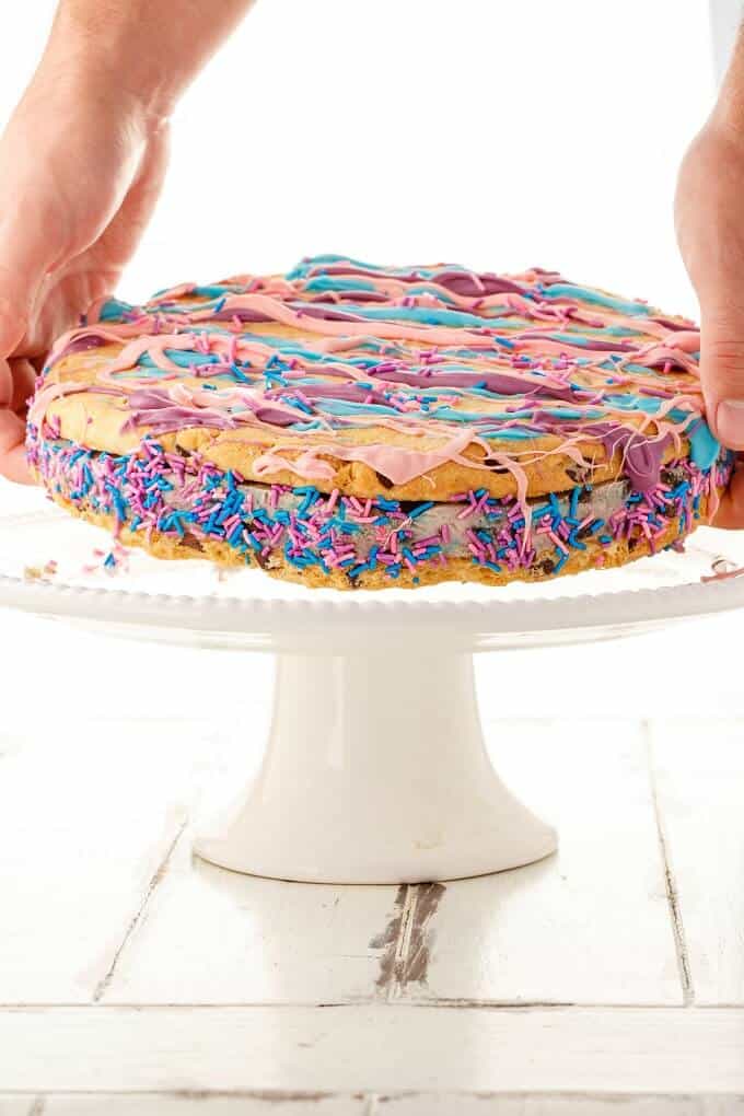 Giant Chocolate Chip Cookie Ice Cream Sandwich held by hands over white tray on white table