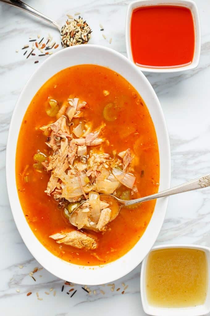 Tomato Turkey Soup with Wild Rice on white palte with spoon, small white bowls with soup around