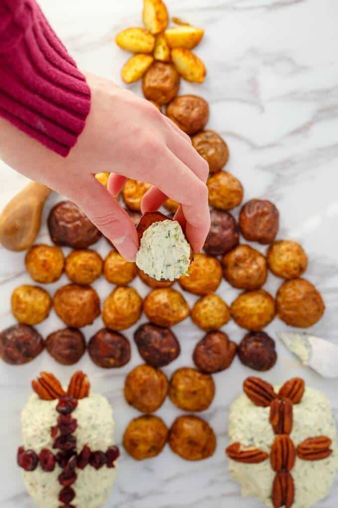 Holiday Cheese Ball with Roasted Potatoes on white background, one potato held by hand