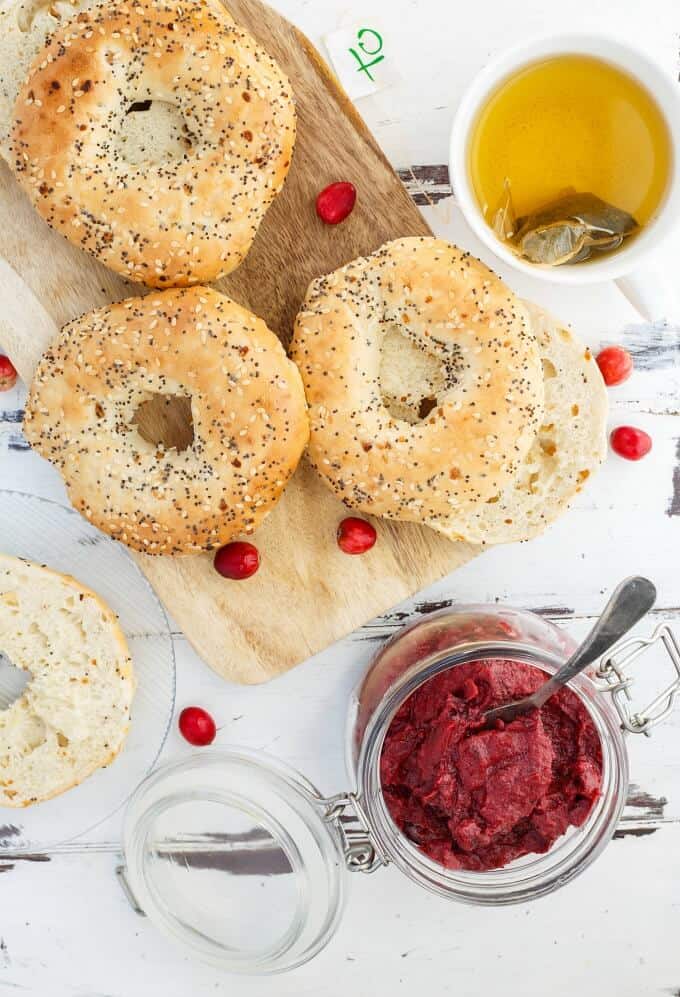 Slow Cooker Cranberry Butter in glass jar with spoon nexto to doughnuts on wooden pad with cranberries (Vegan/GF)