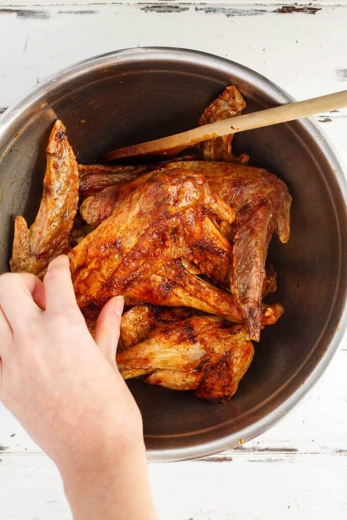 Zesty Maple Turkey Wings in pot with wooden spatula , wing touched by hand