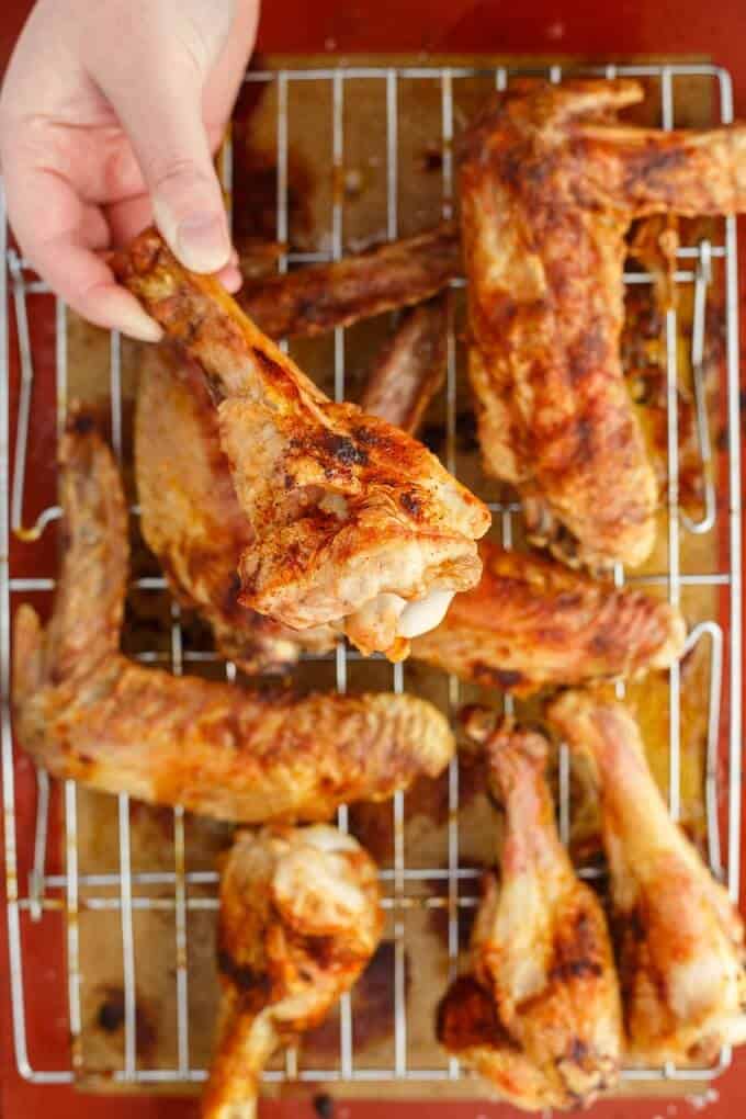 Zesty Maple Turkey Wings on baking grid, one wing held by hand