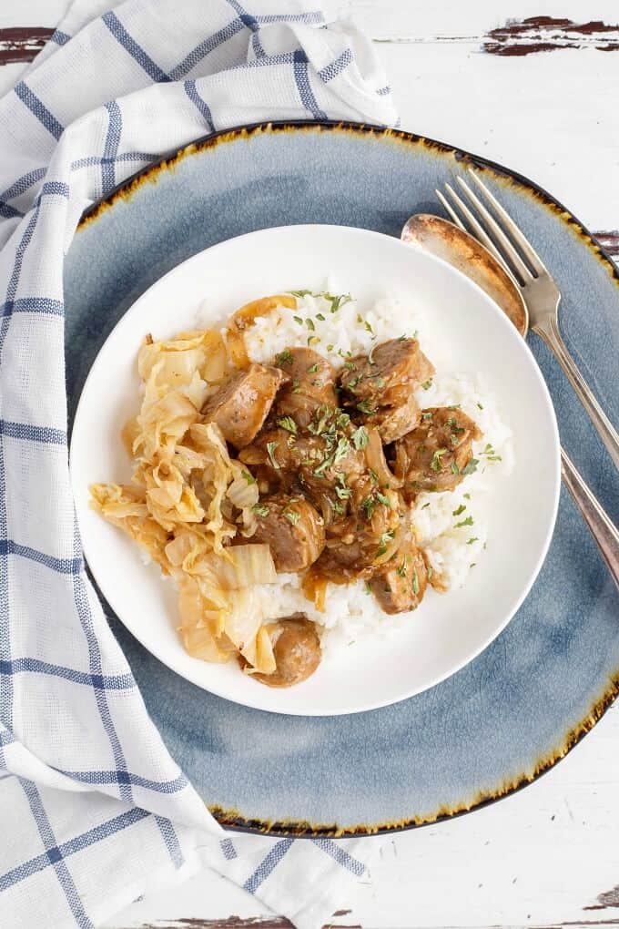 Beer Gravy Sausage Dinner on white plate on gray tray with spoon and fork