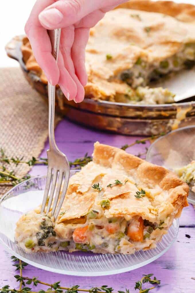 Hearty Vegetarian Pot Pie on glass tray and glass plate with fork held by hand