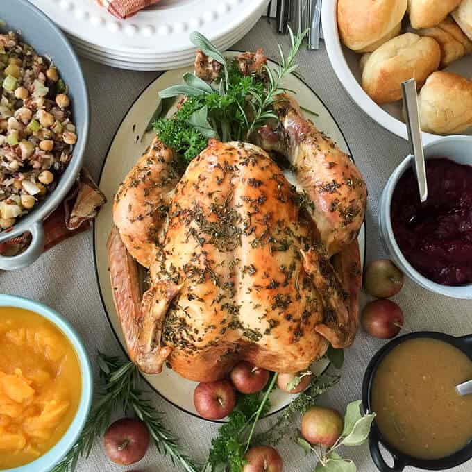 Roast turkey with pan gravy on tray with many ingredients in bowls around