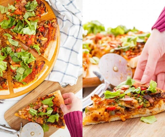 Turkey Bacon Cheeseburger Pizza on wooden pad being sliced by pizza cutter, pizza slice held by hand