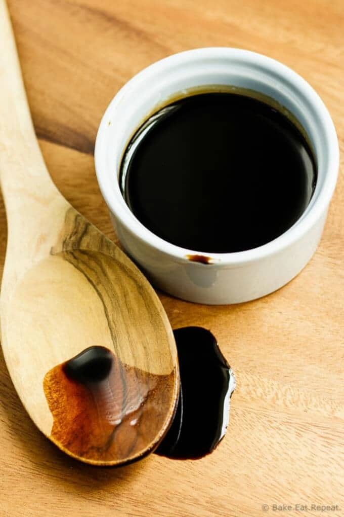 Homemade balsamic glaze in white bowl and on wooden spoon
