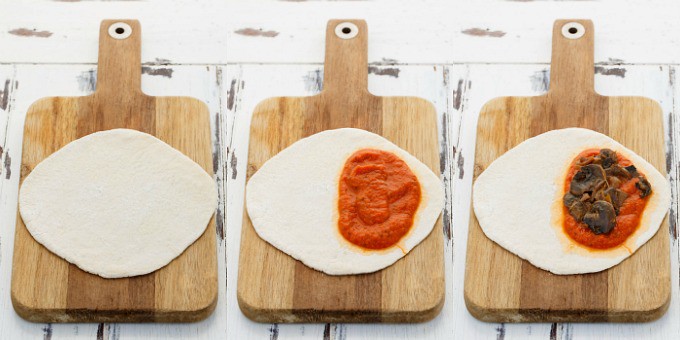 Homemade Pizza Pockets  rolled dough on wooden pad being topped.