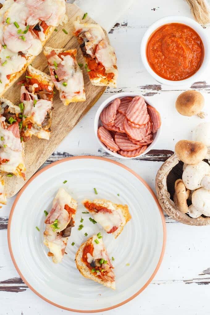 Turkey Pizza Bread  on wooden pad and white plate, turkey and sauce in white bowls and mushrooms on white table