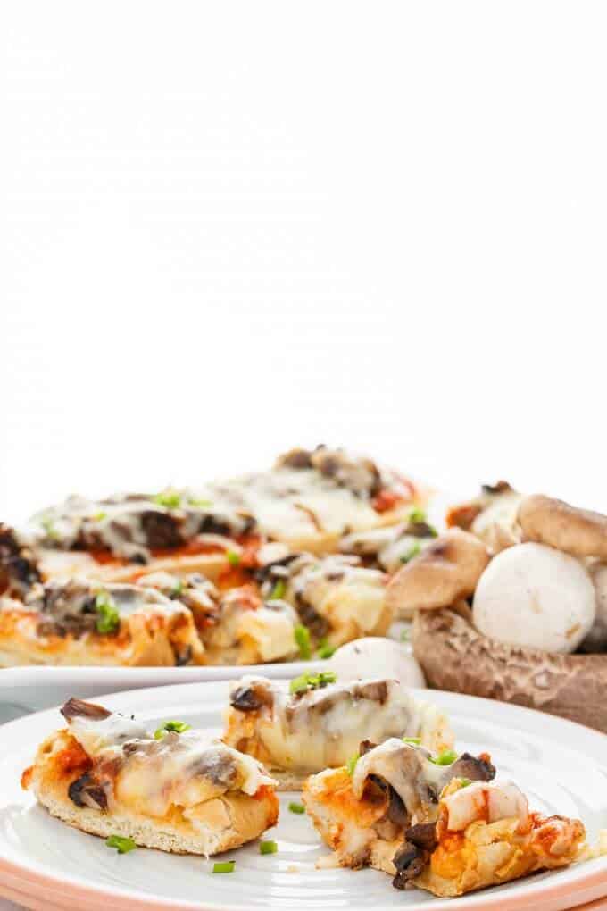Vegetarian Mushroom Pizza Bread  on white plate and white tray with mushrooms on table