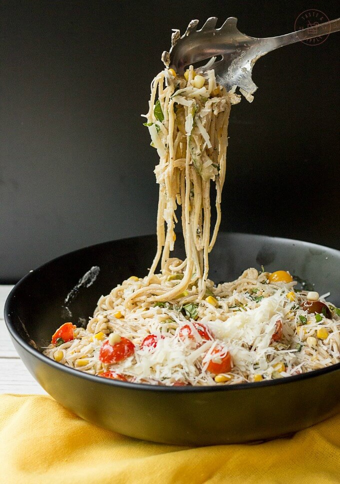 Goat cheese pasta primavera on black pan picked by spoon