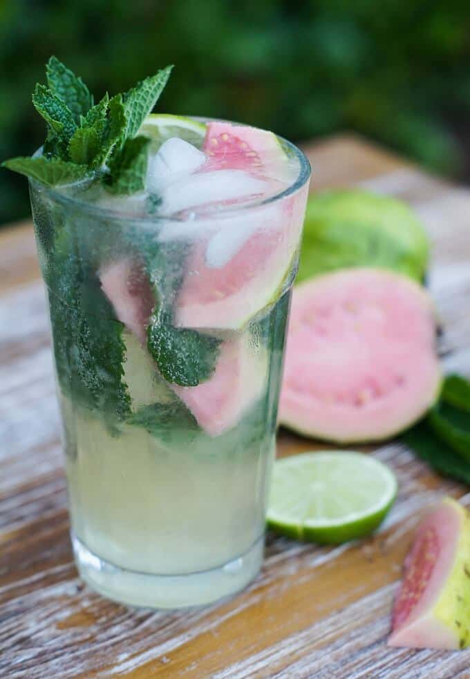 Guava mojito in glass cup with slices of lime and guava on the table