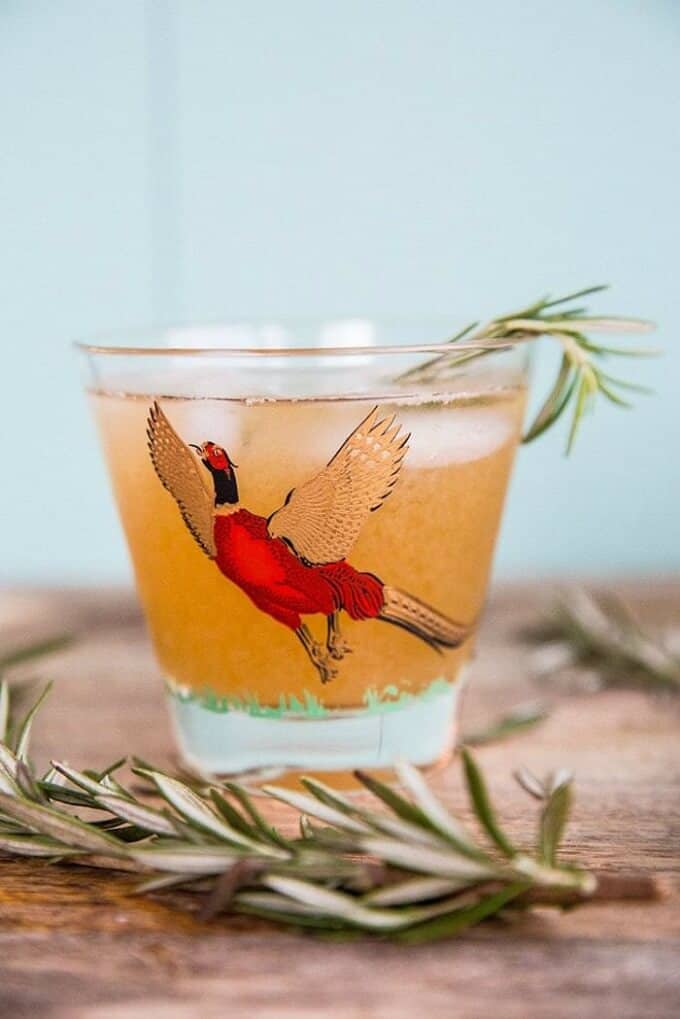 Maple rosemary bourbon sour in glass cup with herbs