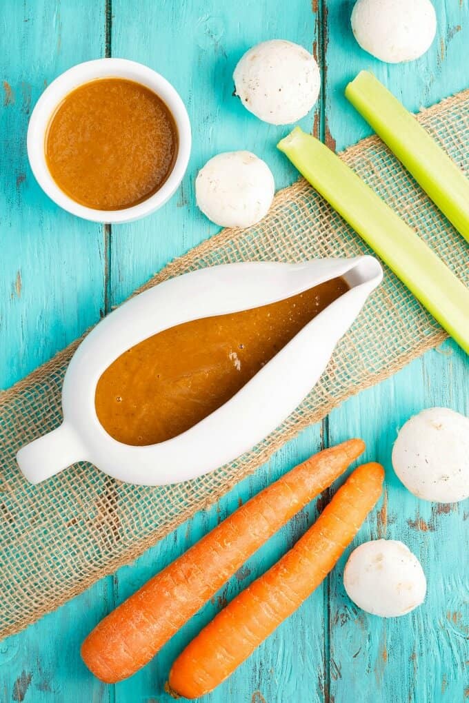 Vegetarian Mushroom Gravy  in white bowls with vegetable and mushrooms on blue table