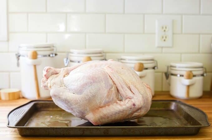 Turkey on gray baking pot. Cooking pots with wooden spatulas on table in the background