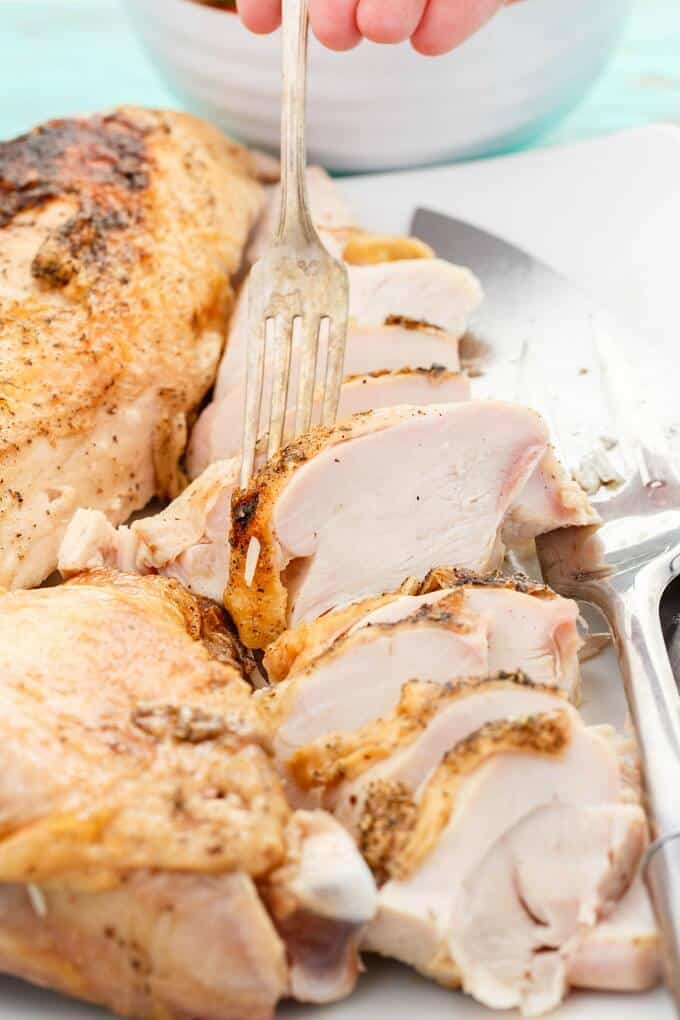 Grilled Spatchcock Turkey on white tray with forks, close view. White bowl in the background