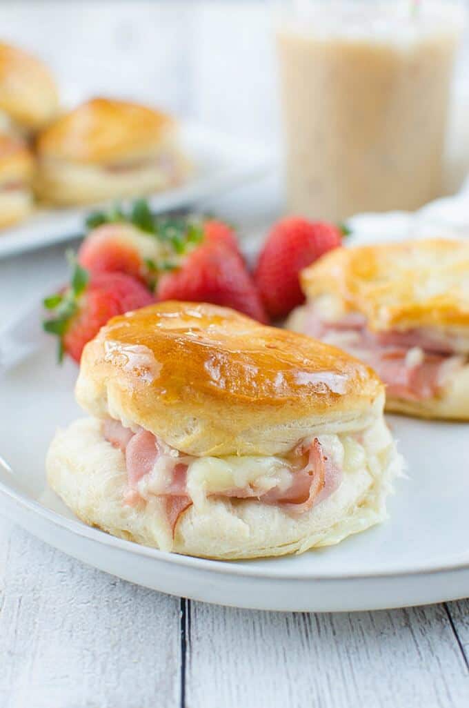 Honey ham biscuits on white plate with ripe strawberries