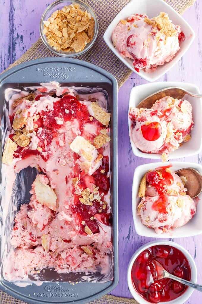 Cherry Pie Ice Cream  in black container and in white bowls with spoons. Bowl swith ingredients on purple table