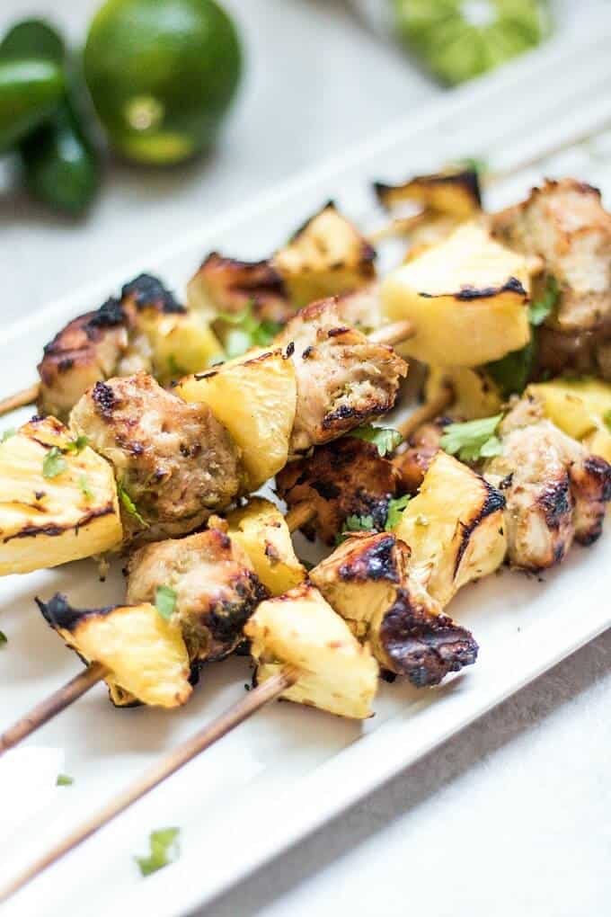 Grilled jerk chicken kabobs with pineaple on white tray