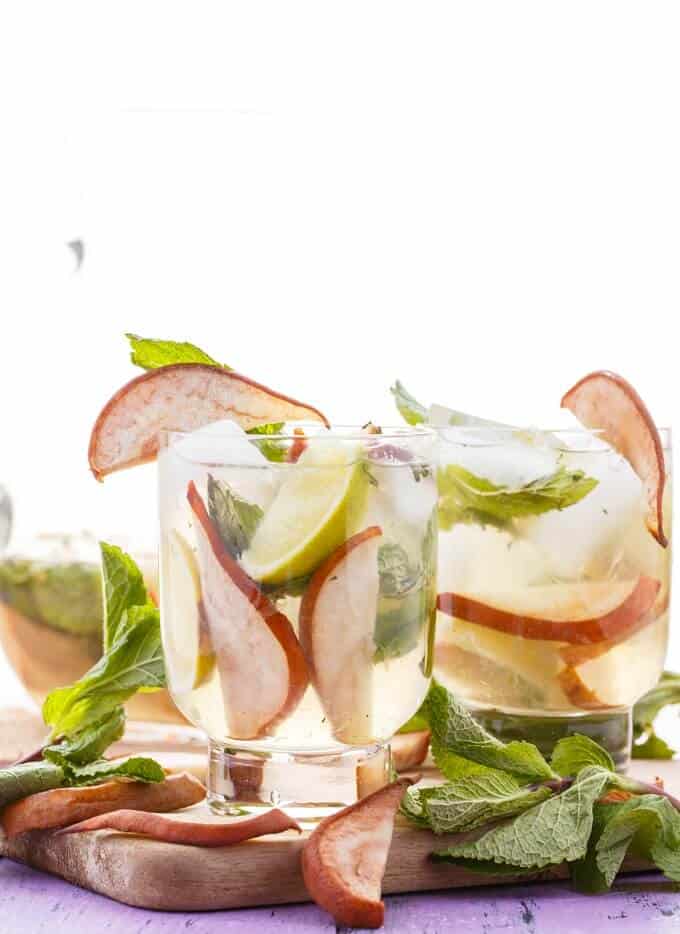 Roasted Pear Mojitos  in glass cups on wooden pad with herbs and sliced roasted pears
