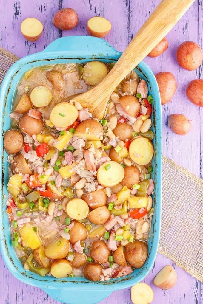 Baked Hawaiian Potato in blue Casserole  with wooden spatula on pruple table with potatoes