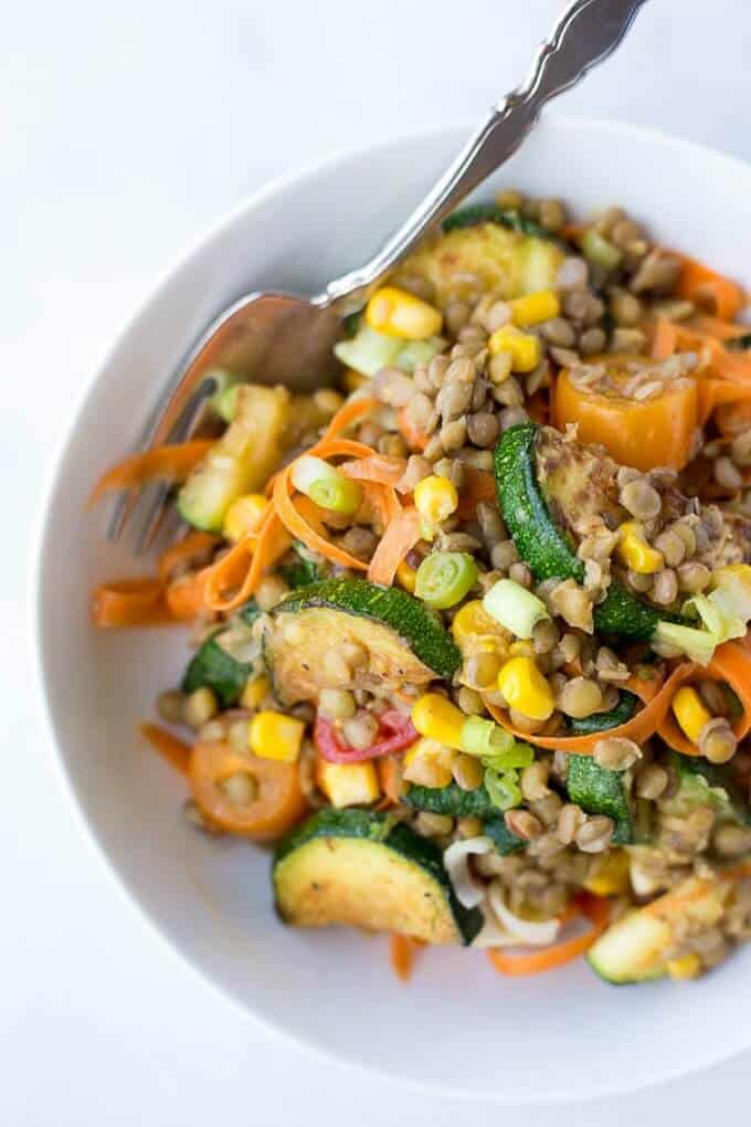 Honey mustard lentil vegetable salad in white bowl with fork