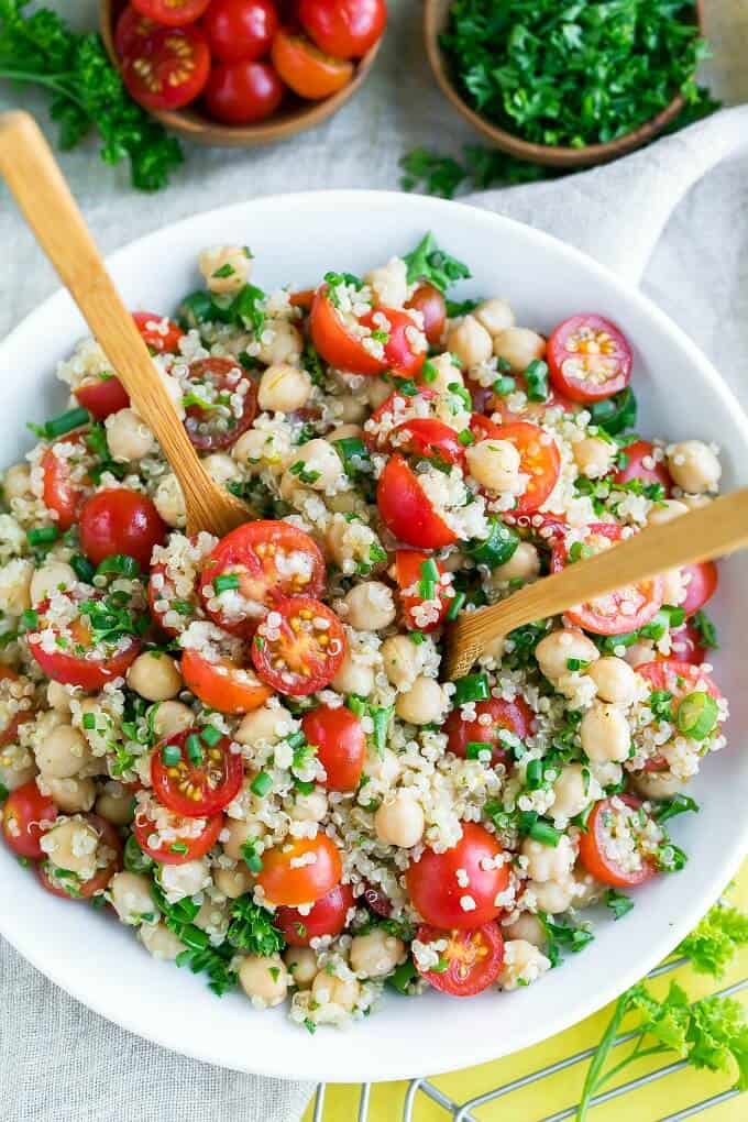 Tomato quinoa salat in white bowl with wooden spoons