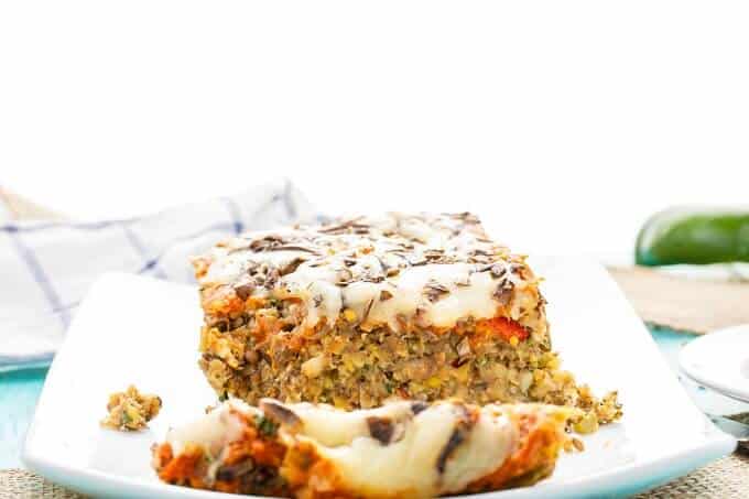 Vegetarian Pizza Meatloaf partially sliced  on white tray with cloth wipe and vegetable  in the background