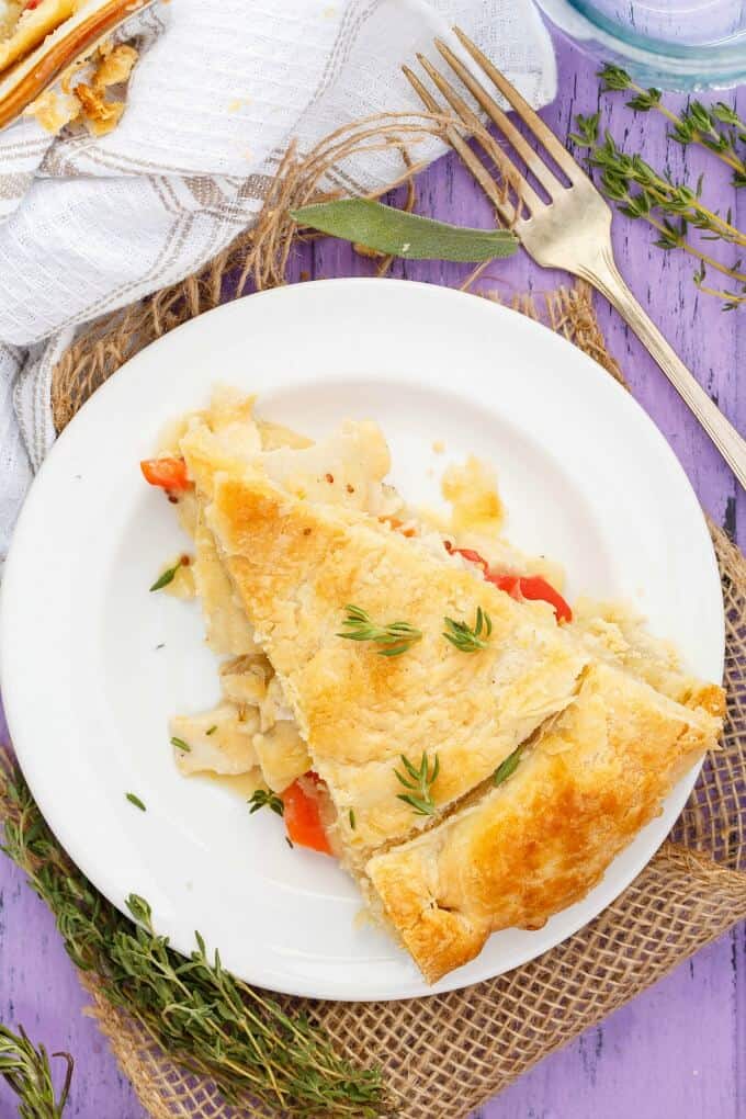 Homemade Turkey Pot Pie  on white plate with fork and herbs on purple table