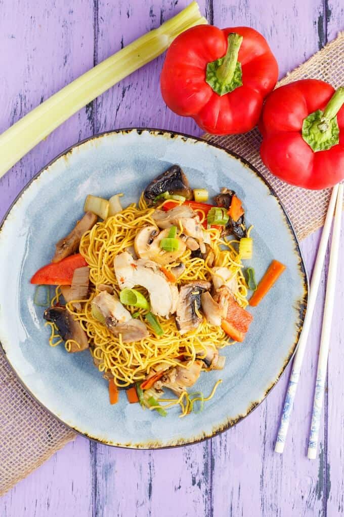 Leftover Turkey Stir Fry  on blue plate. Sticks, celery and red peppers on purple table