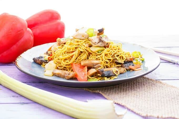 Leftover Turkey Stir Fry on blue plate with celery, red peppers and sticks on purple table