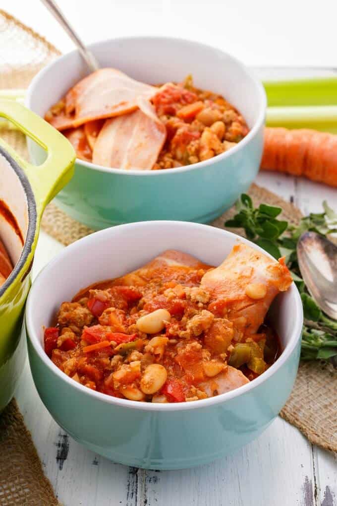 Turkey Bacon Chili in blue bowls with spoon. Vegetable, herbs, spoon on the table