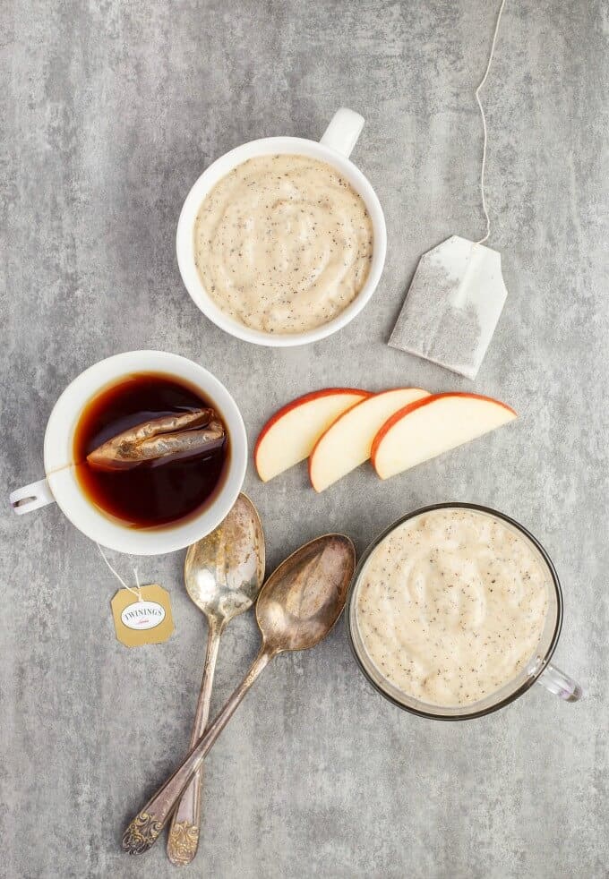 Homemade Earl Grey Pudding in cups with apples slices, tea bag, spoon, cup of tea on gray table