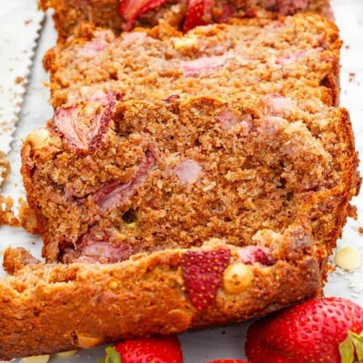 White chocolate strawberry banana bread slices with ripe strawberries on white background