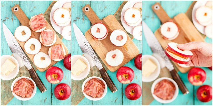 Turkey Bacon Apple Sandwich with Cheese held by hand over wooden pad with apples, bowls of ingredients, knife, brown cloth on blue table. Sandwiches process of making